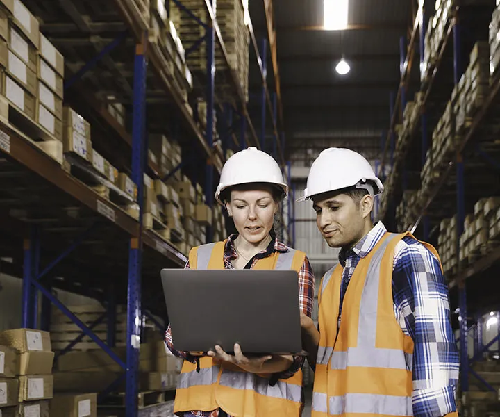 Logistic worker staff colleague in safety suit holding computer laptop working in a warehouse store